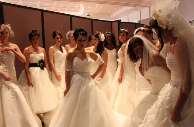 Models in wedding gowns backstage at a bridal show