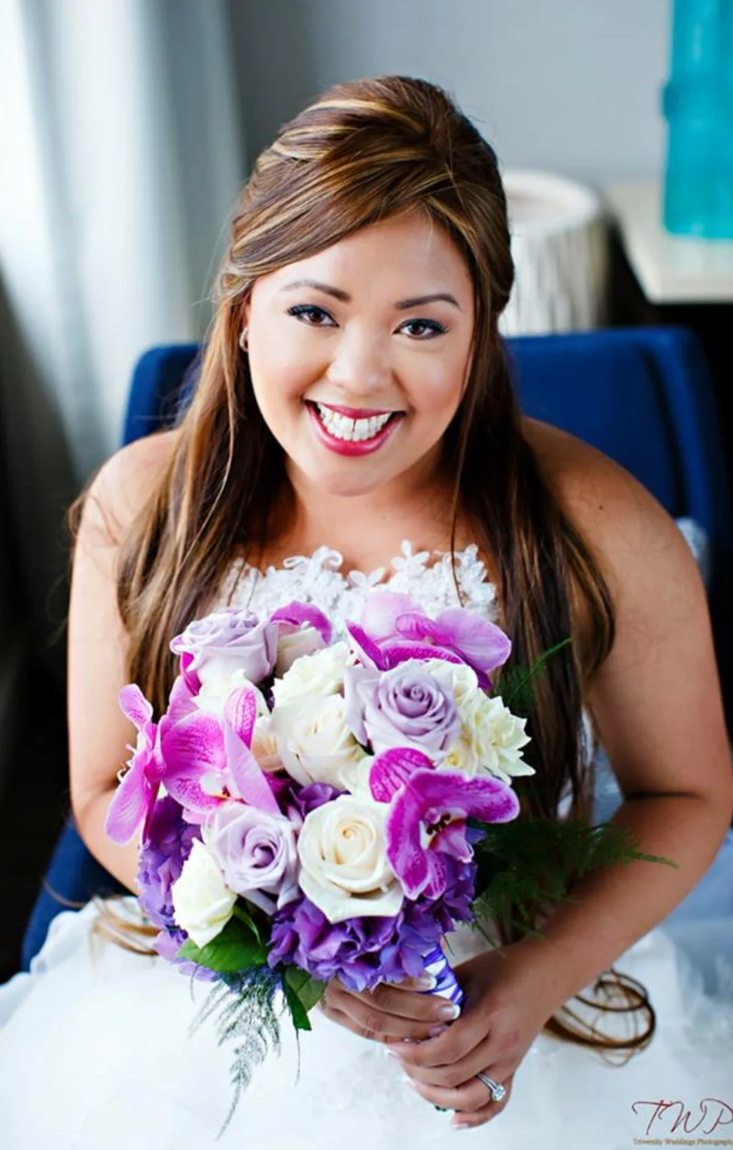 Bride with soft curled updo holding a purple bouquet
